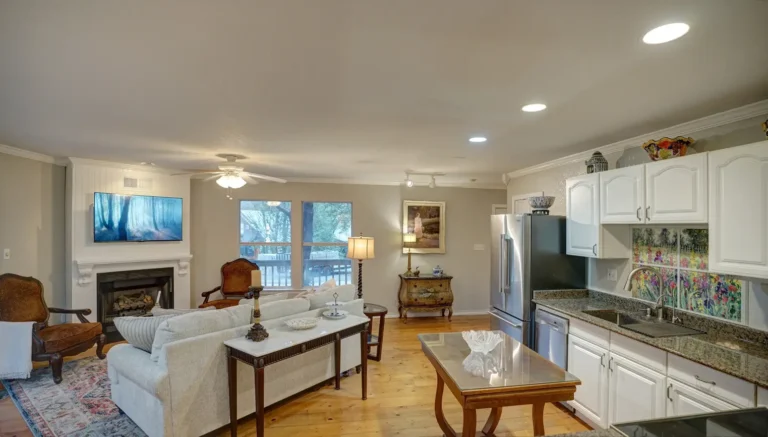 Living room and kitchen view with sofa, TV, and white cabinets.